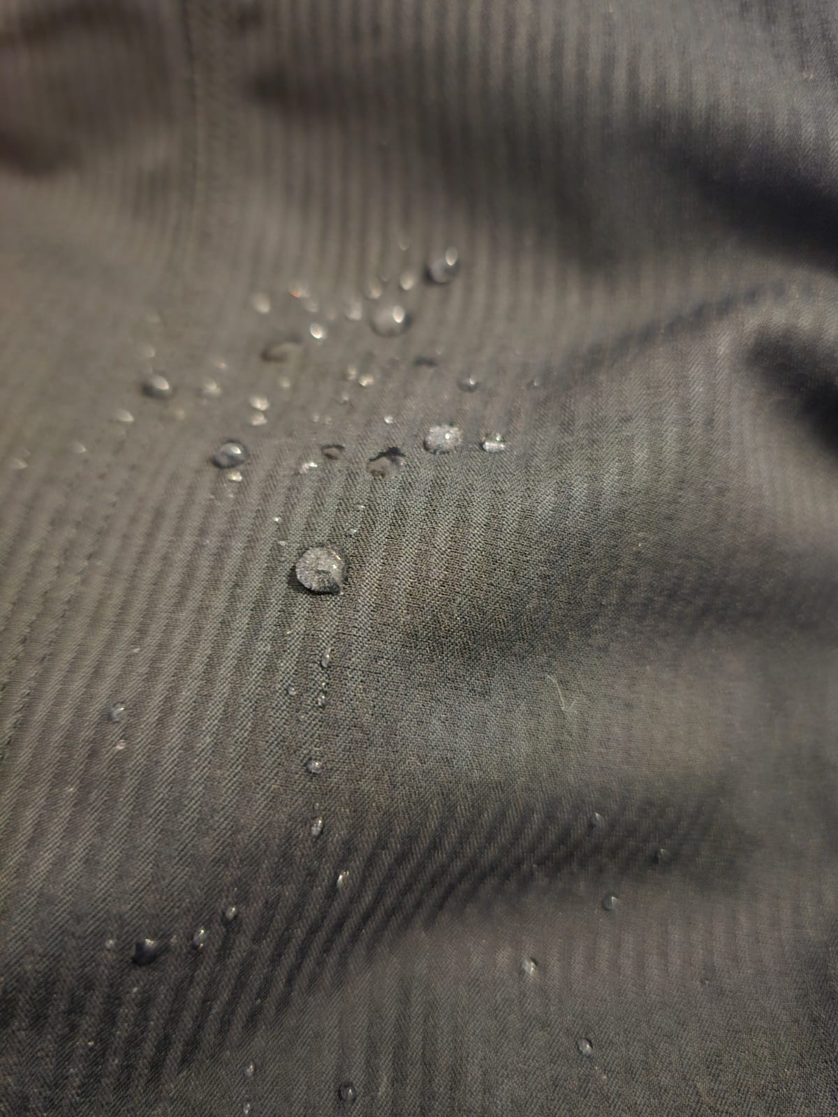 Close-up of a textured Charcoal fabric with water droplets on it